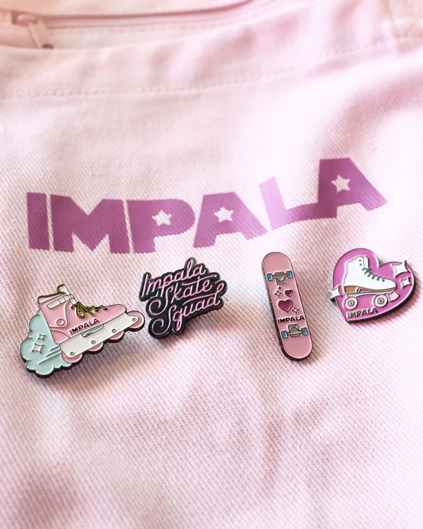 Skate-themed enamel pins on white fabric: logo, heart, deck, and shoe designs
