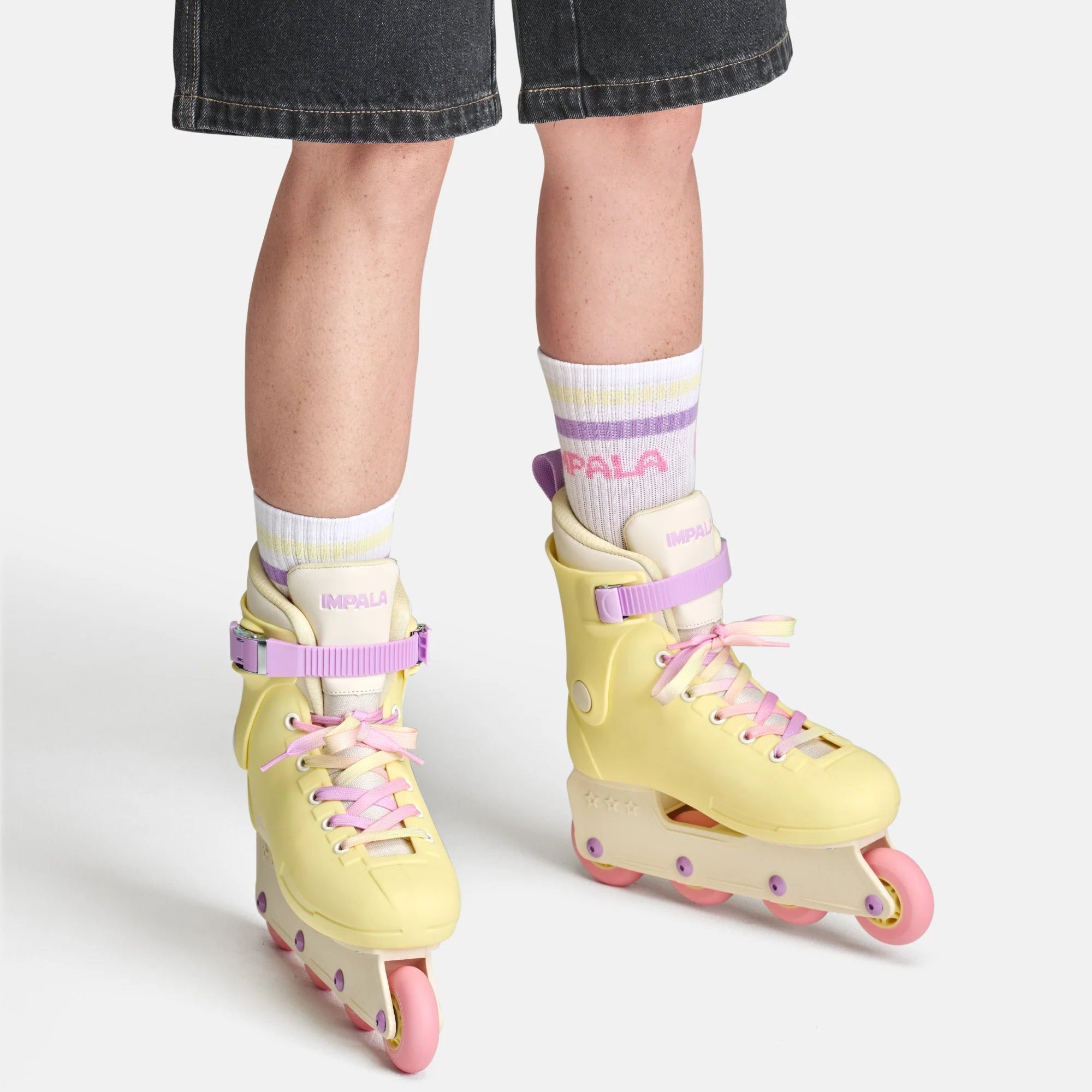 Impala buttercup yellow inline skates on feet with pink laces and purple straps