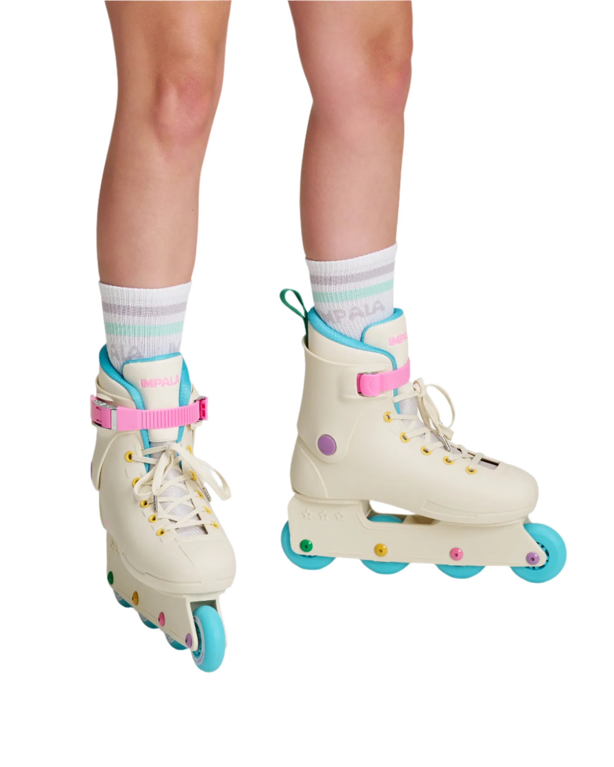 Cream inline skates on legs; white laces, pink straps, teal wheels