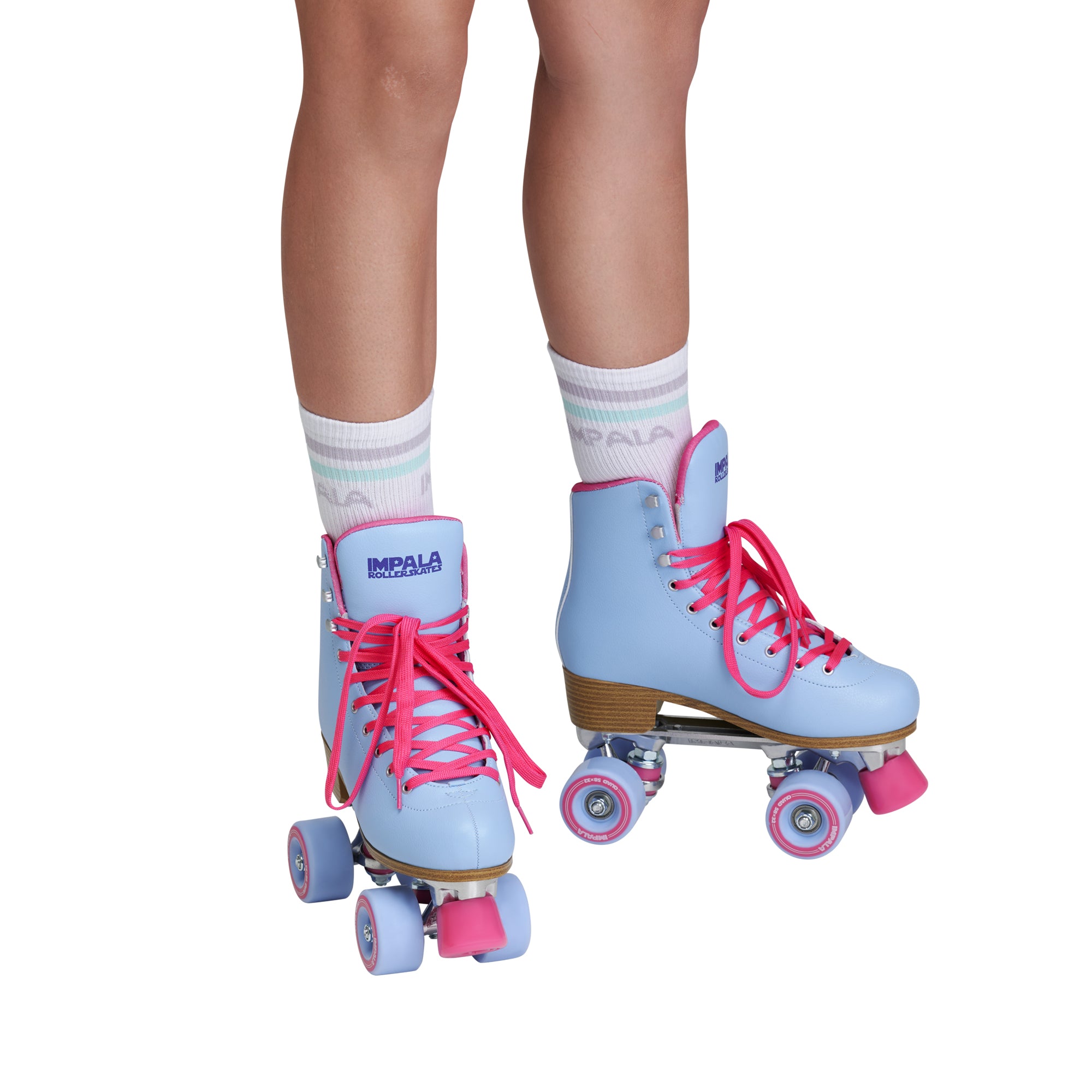 Light blue quad roller skates on feet with pink laces and light purple wheels