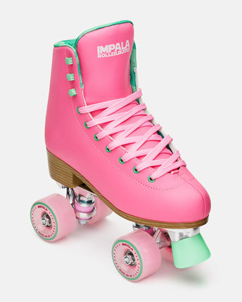 Pink high-top quad skates with green laces, roller wheels, and tan wooden outsole