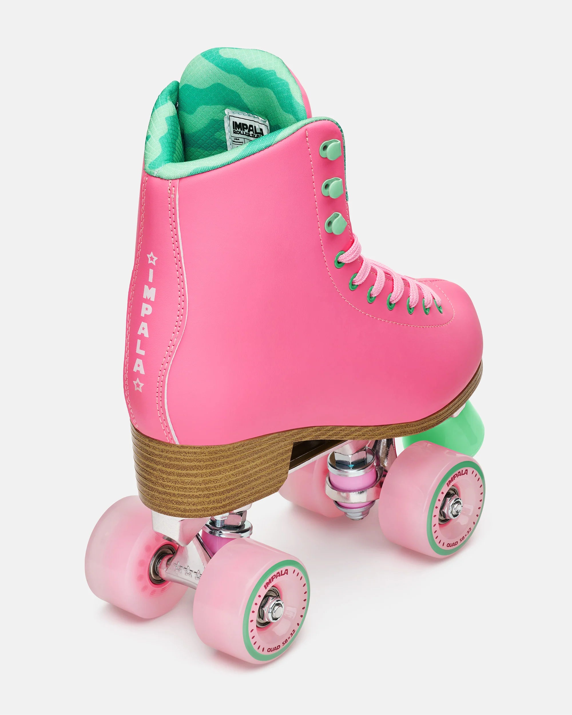 Pink high-top quad skates with green lining, wooden sole, and four pink wheels