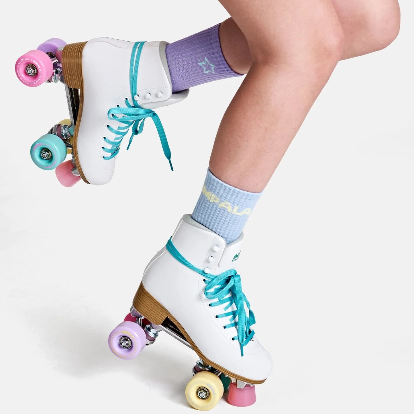 Quad roller skates with pastel wheels in pink, purple, teal, and yellow.
