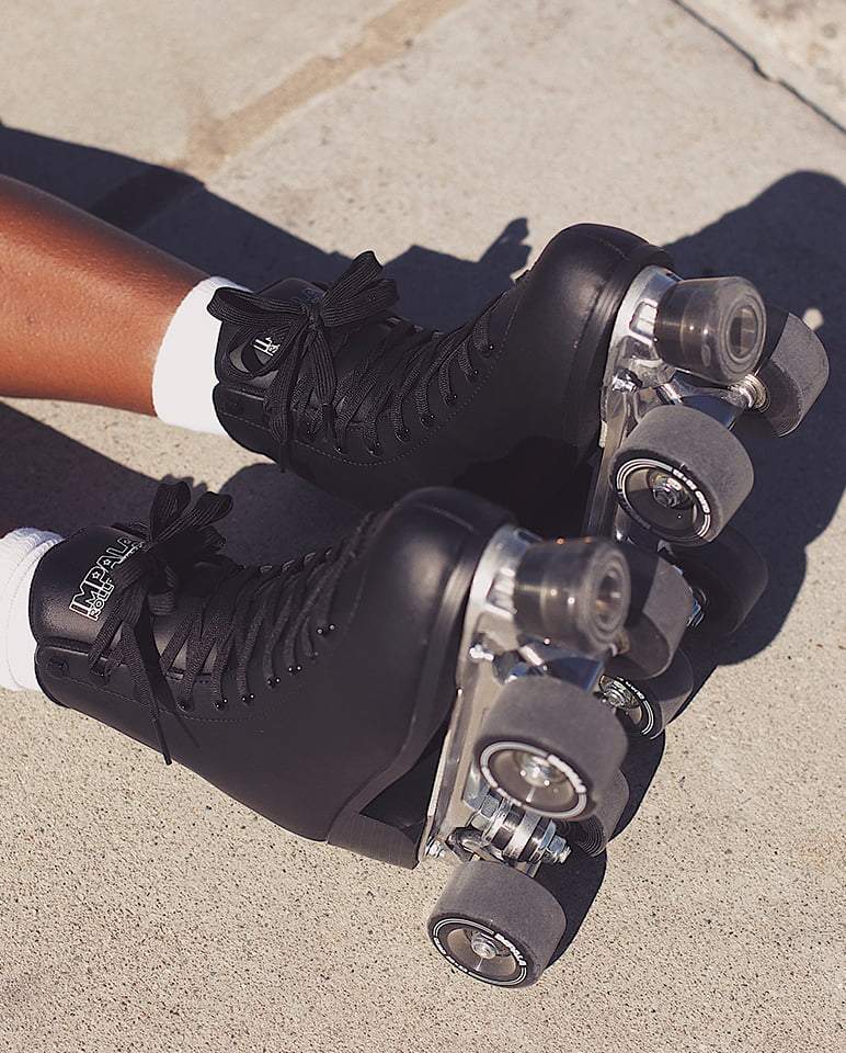 Black quad skates on feet with visible four-wheel trucks and laces