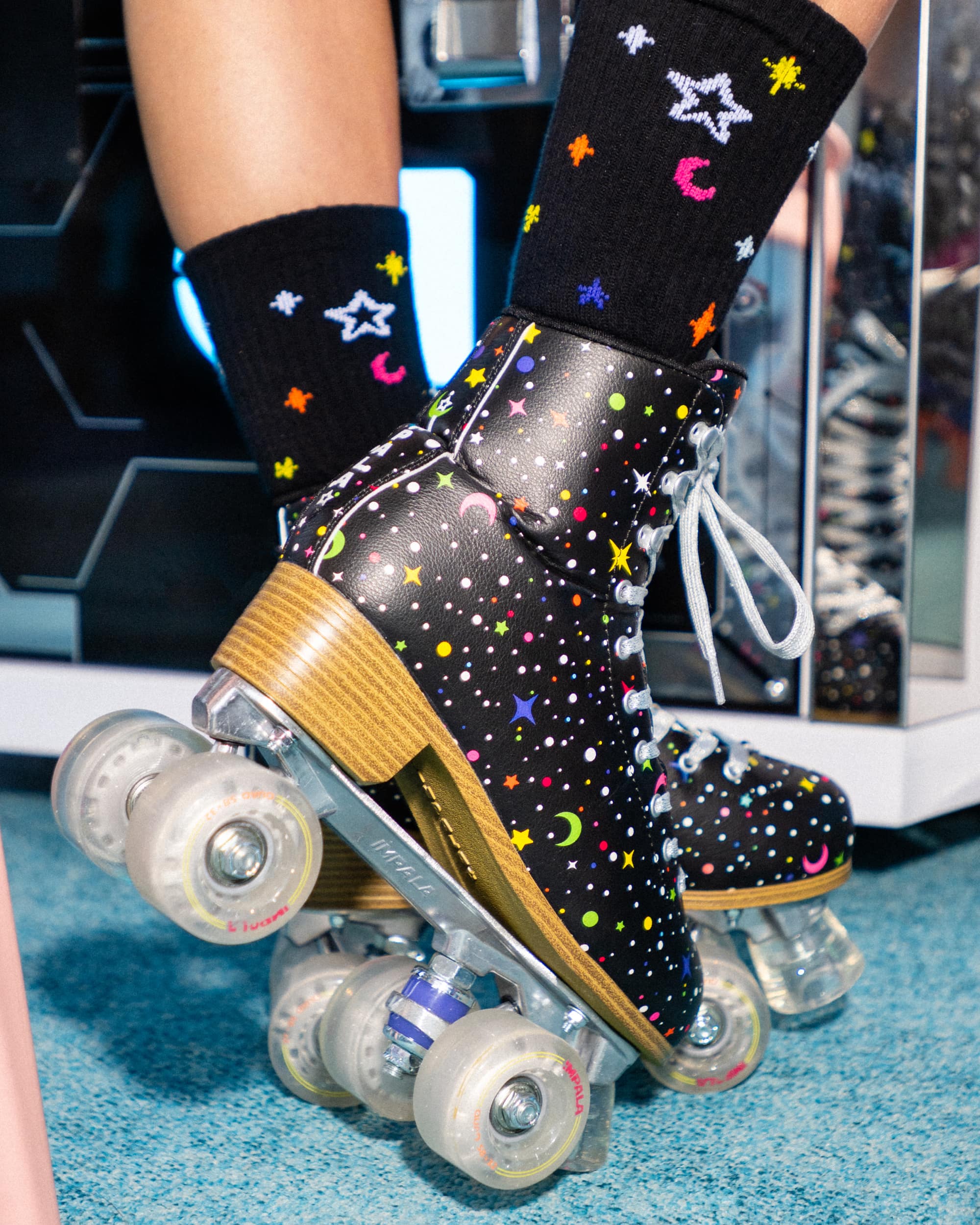 Black twinkle skate socks with colorful stars and moons, worn with roller skates
