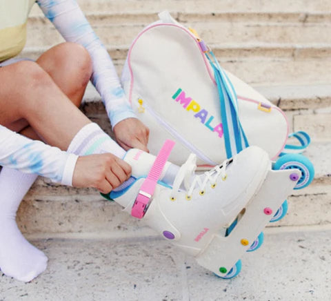 Pair of cream inline skates with pink strap and multicolor wheel accents