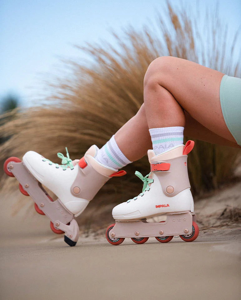 Beige inline skates with orange wheels and mint-green laces worn outdoors