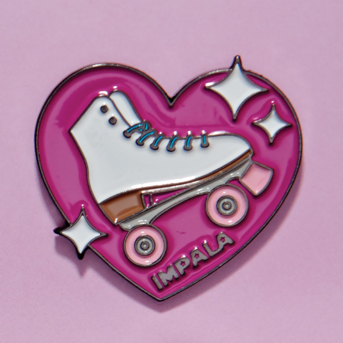 Heart-shaped enamel pin with white skate shoe, pink background, and star accents