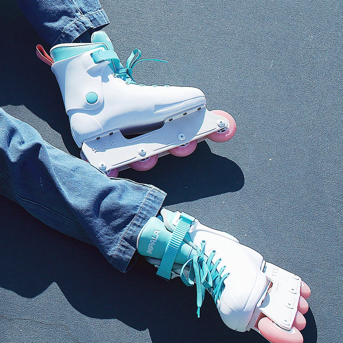 Person wearing white inline skates with mint accents and pink wheel detailing