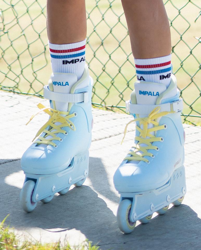 Pair of sky blue inline skates with yellow laces, blue socks, and front wheels