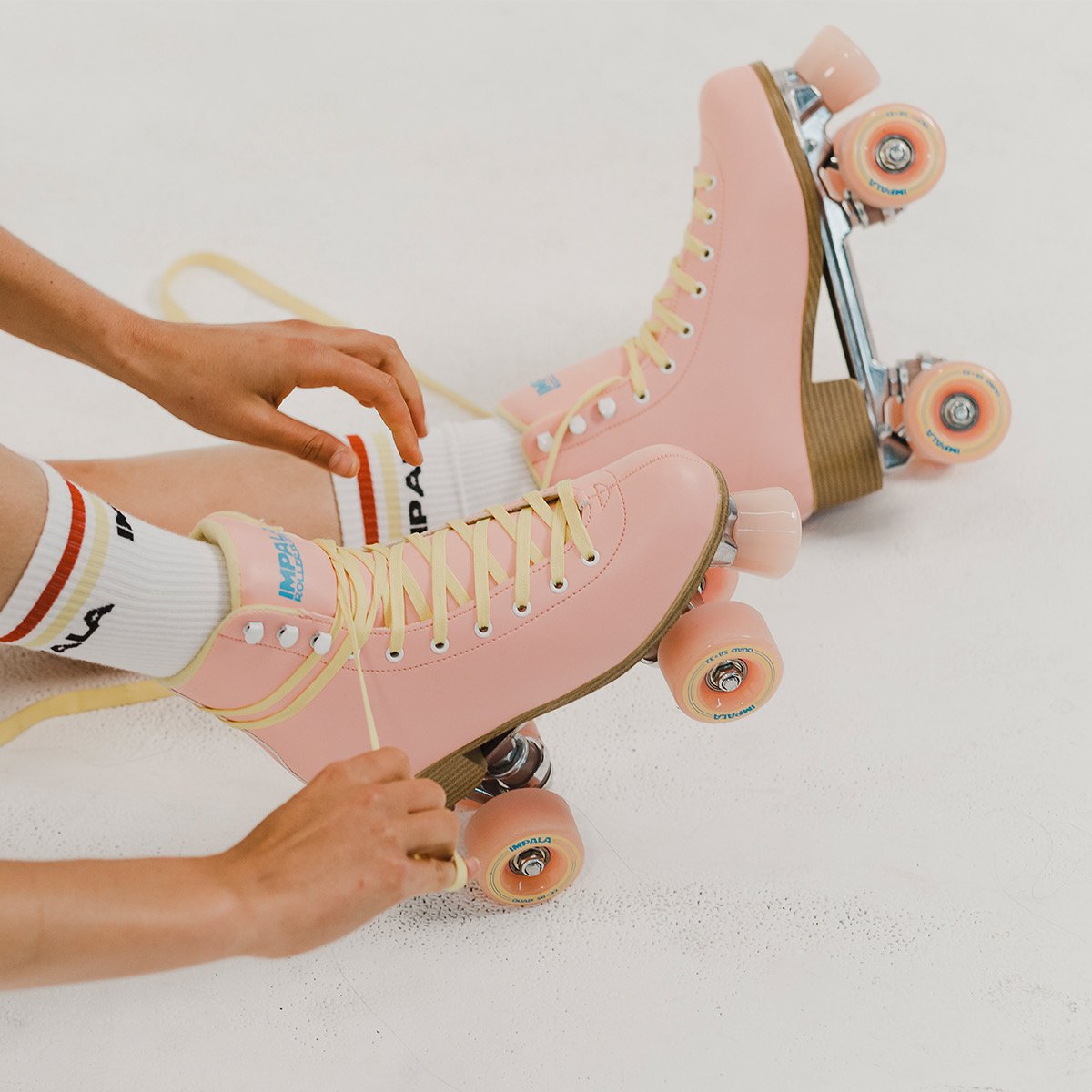 Pink Impala quad roller skates with orange wheels and tan suede-style cuffs
