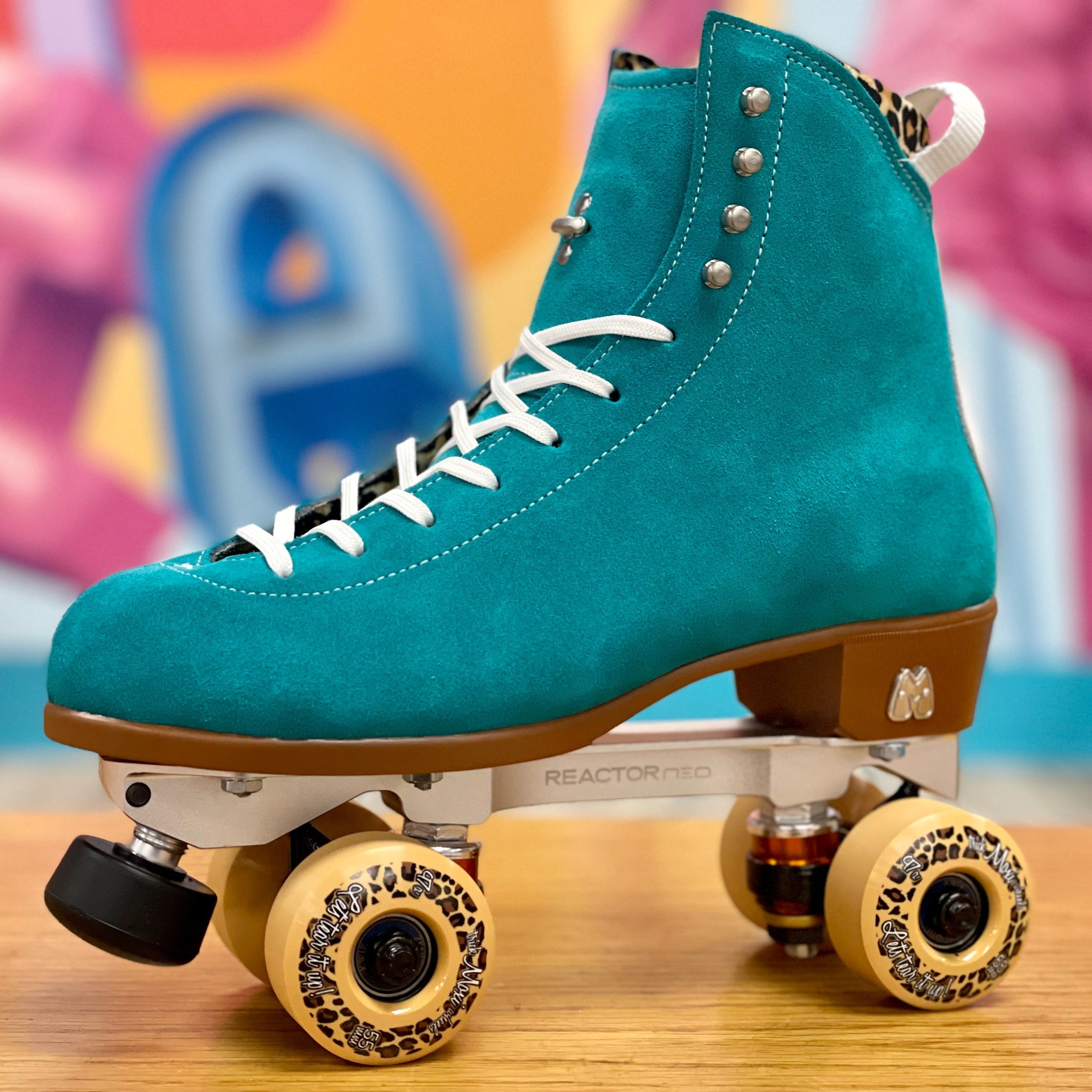 Teal high-top skate boot with white laces mounted on quad roller skate wheels