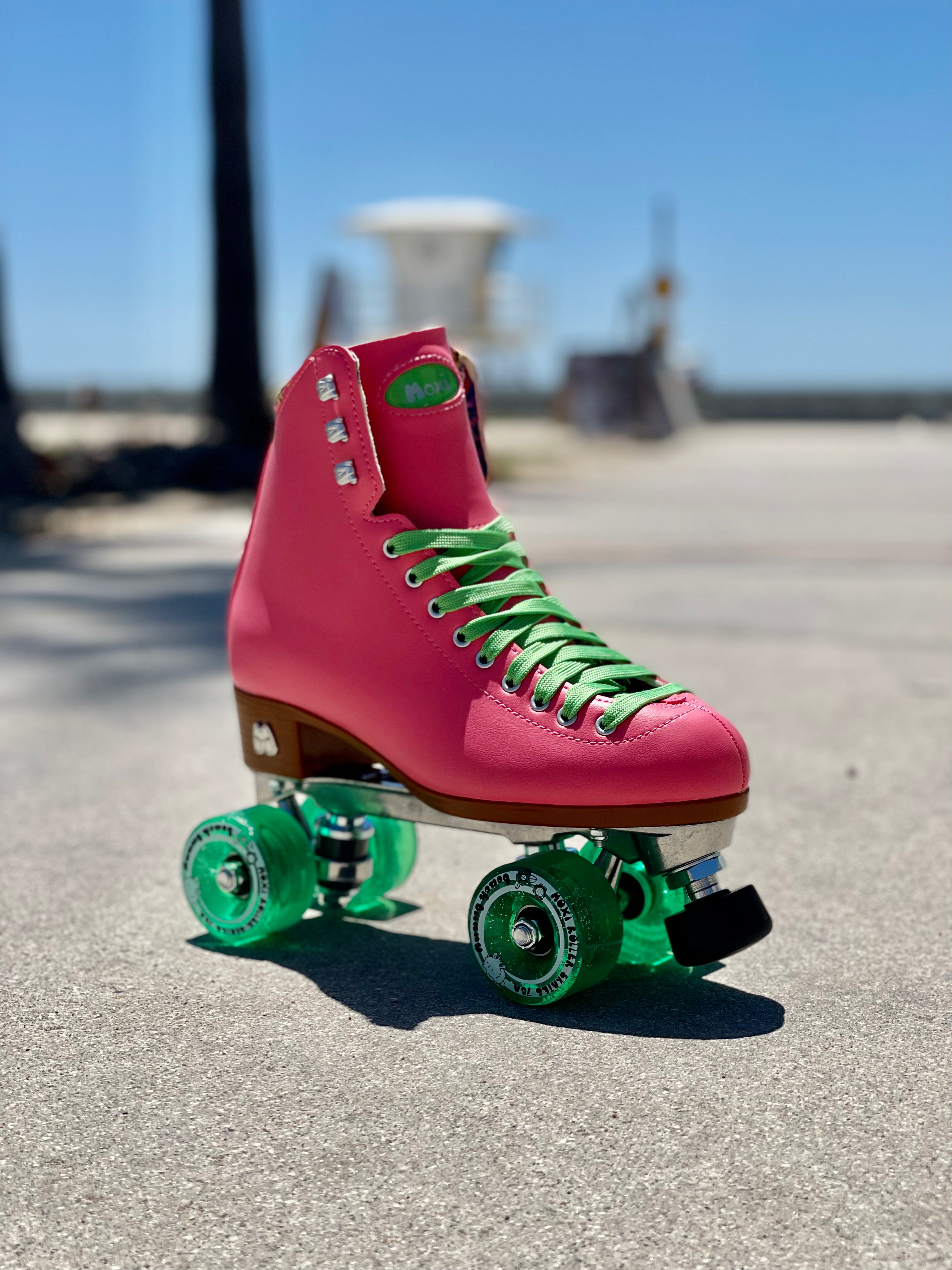 Pink roller skates with green quad wheels and green laces, angled side view